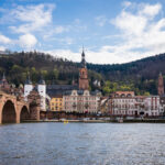 Blick über den Neckar auf die Altstadt von Heidelberg mit Alter Brücke und Heiliggeistkirche.