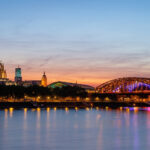 Kölner Dom und Hohenzollernbrücke im Abendlicht mit Spiegelung im Rhein.