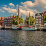 Historische Giebelhäuser in Lübeck an der Trave mit festgemachten Segelbooten bei Sonnenschein.