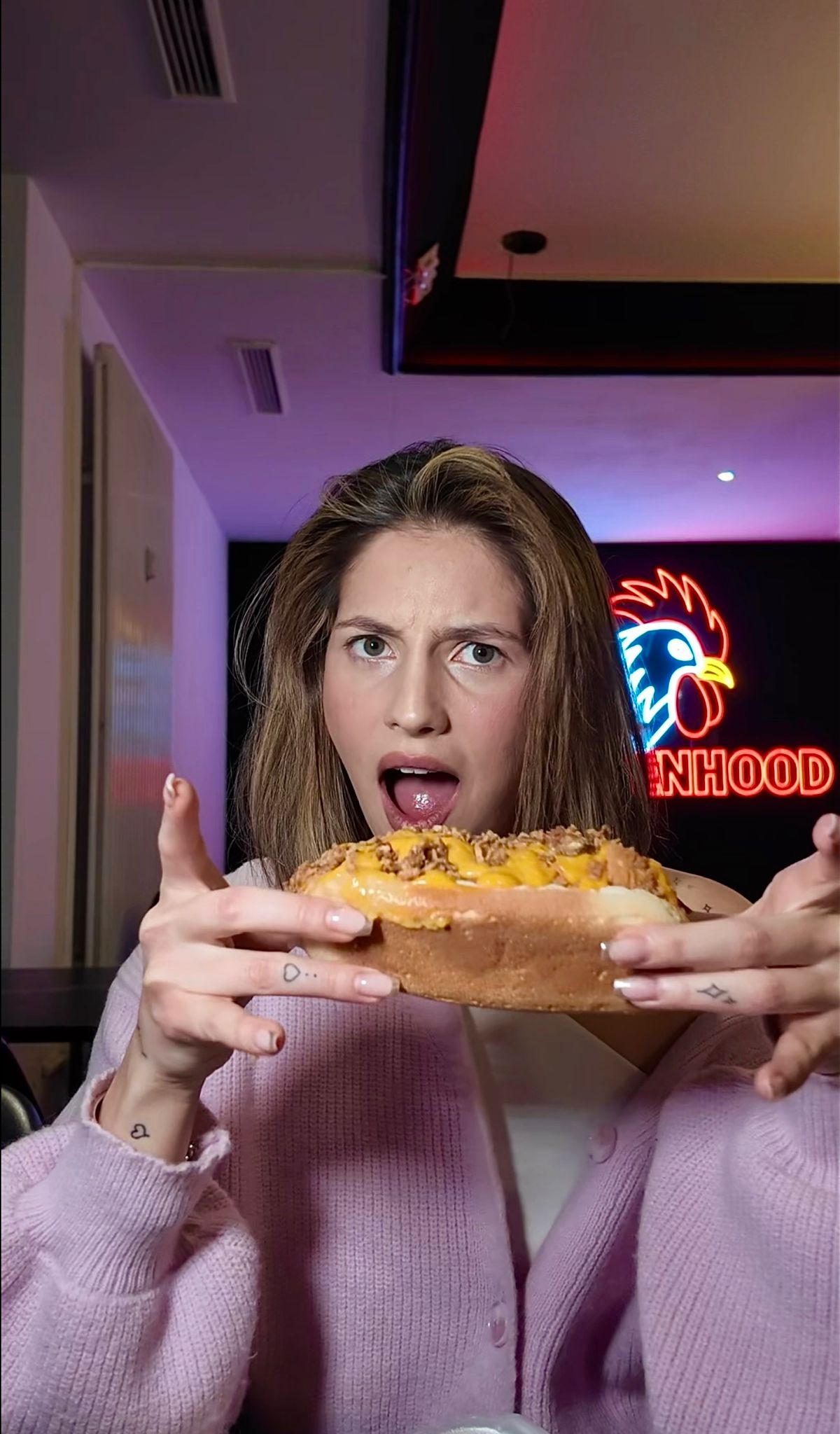 Frau präsentiert einen überbackenen Hotdog im Chickenhood Datteln mit Überraschungsausdruck