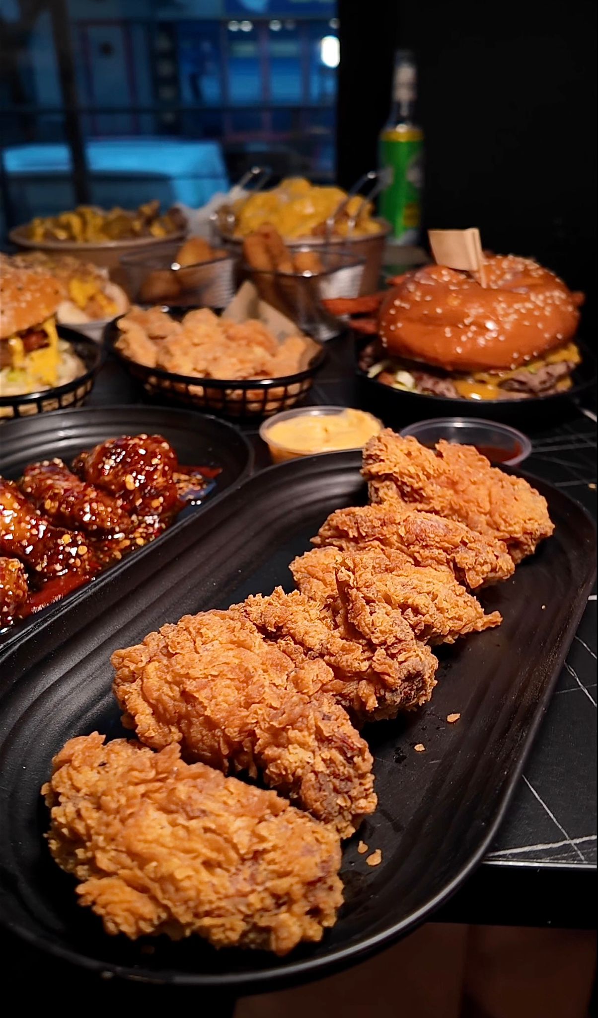 Knusprige Chicken Wings, Burger und Beilagen im Chickenhood Datteln auf dunklem Tisch