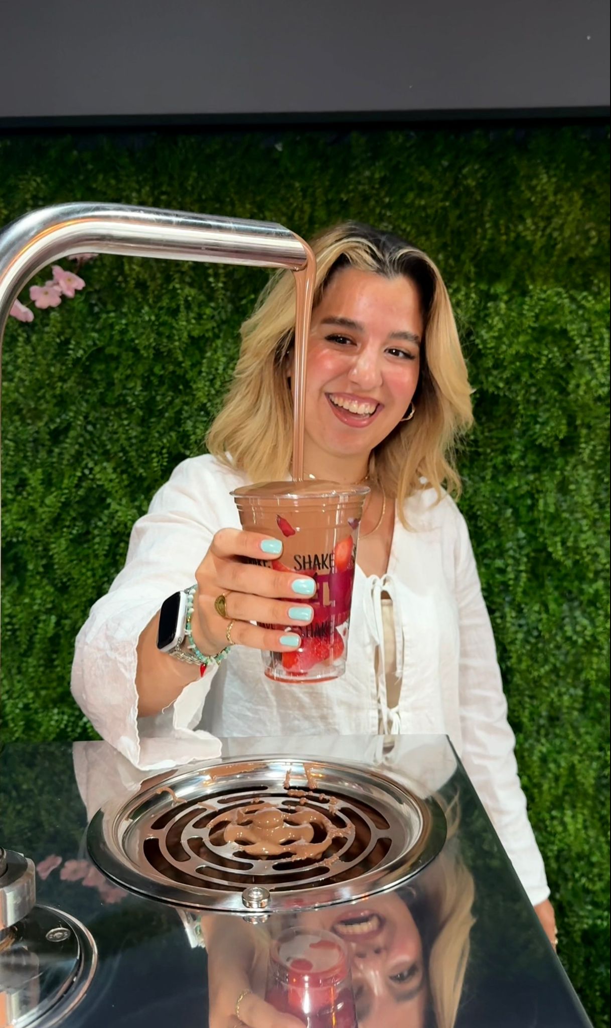 Frau hält einen Becher mit frischen Beeren unter einen Schokobrunnen bei Wonderwaffel Dortmund