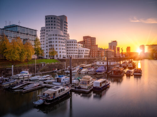 Sonnenuntergang über dem Düsseldorfer MedienHafen mit Blick auf Boote und moderne Architektur