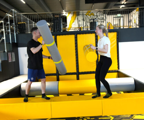Zwei Personen duellieren sich mit Polsterstäben im Battle-Bereich des Cube Funpark Beselich auf einer schmalen Plattform