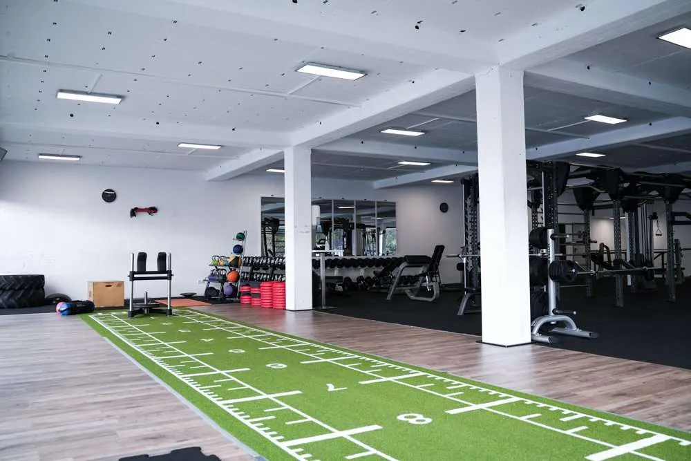 Moderner Functional-Trainingsbereich mit Kunstrasenbahn und Kraftgeräten im Fitness Wellness Loft Schleiden