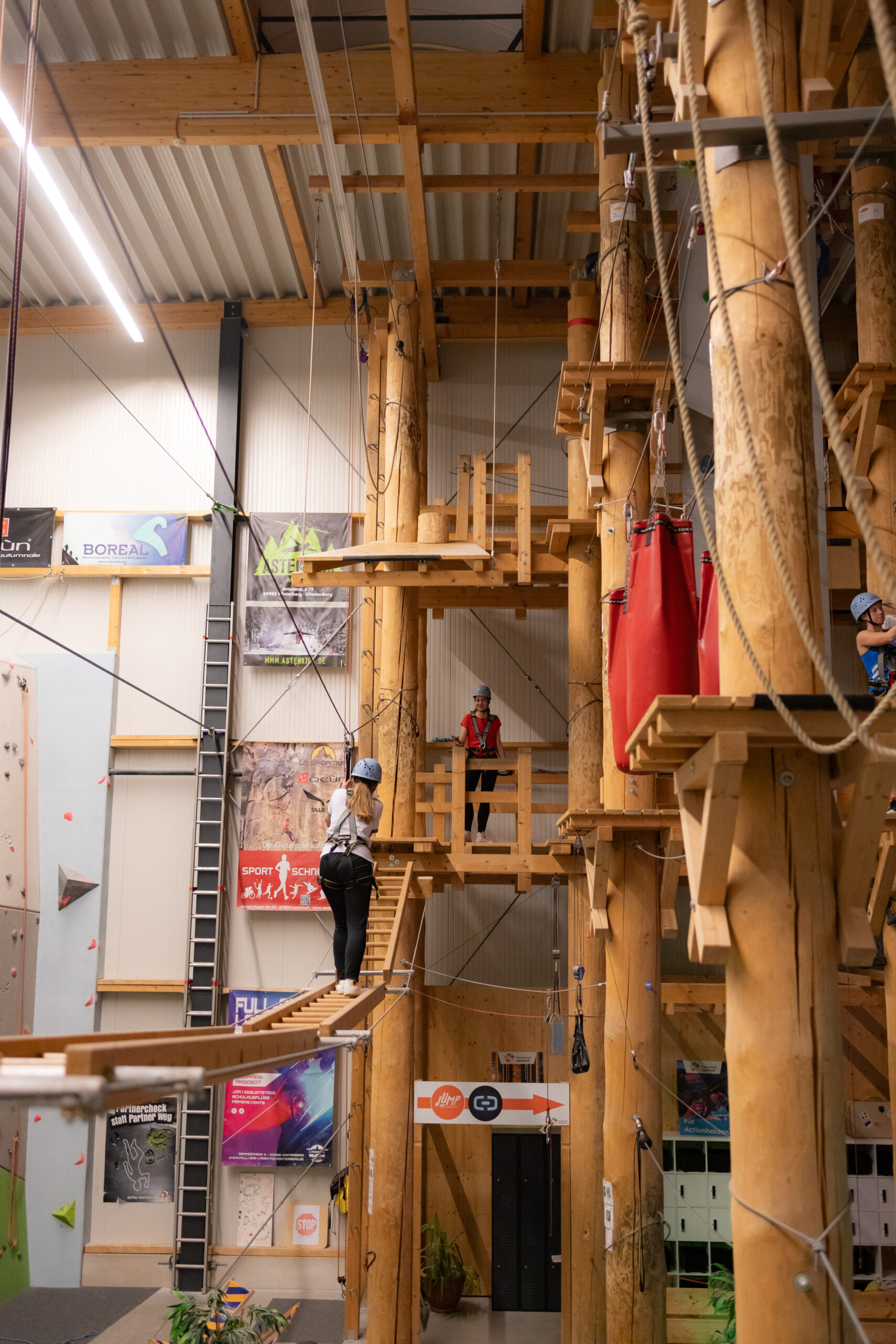 Person balanciert auf einem Seil im Balancierparcours der Freizeitwelt Sauerland, während weitere Teilnehmer in der Höhe aktiv sind