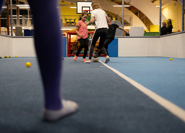 Kinder spielen gemeinsam in der Indoor-Sporthalle der Freizeitwelt Sauerland auf einem blauen Spielfeld