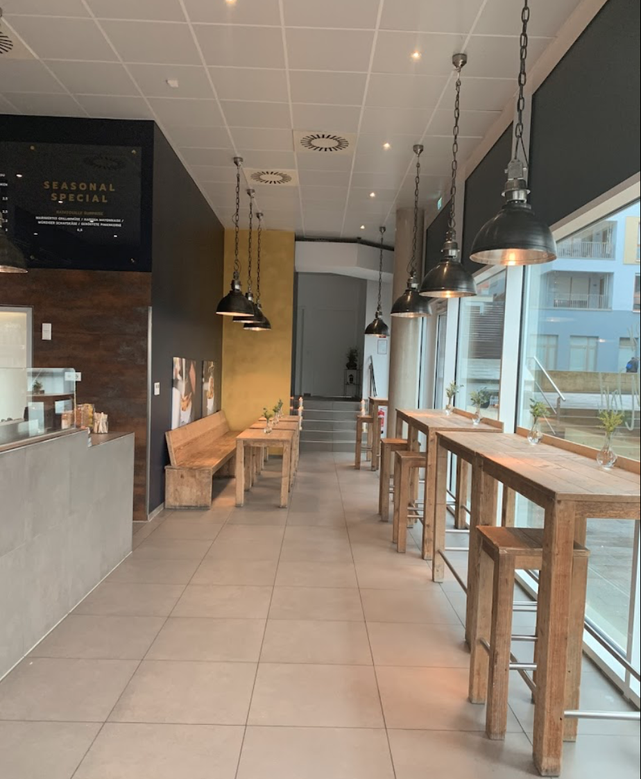 Moderner und gemütlicher Innenbereich der Frittenküche Dortmund mit hohen Sitzplätzen und Holztischen