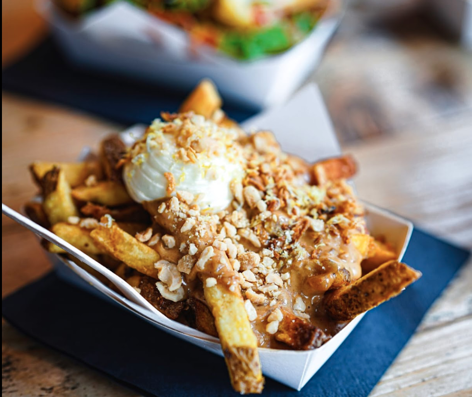Frische Pommes mit cremigem und knusprigem Topping in einer weißen Schale serviert