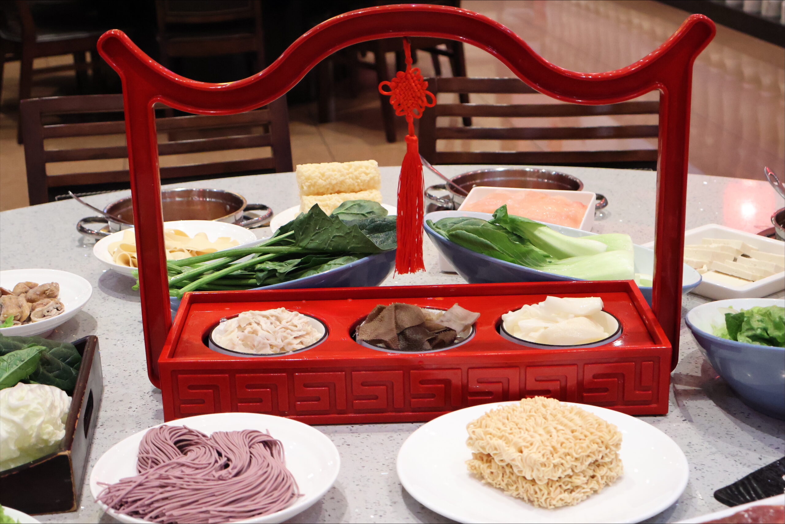 Auswahl frischer Zutaten und Saucen im traditionellen Serviergestell im Kylin Hotpot Dreieich