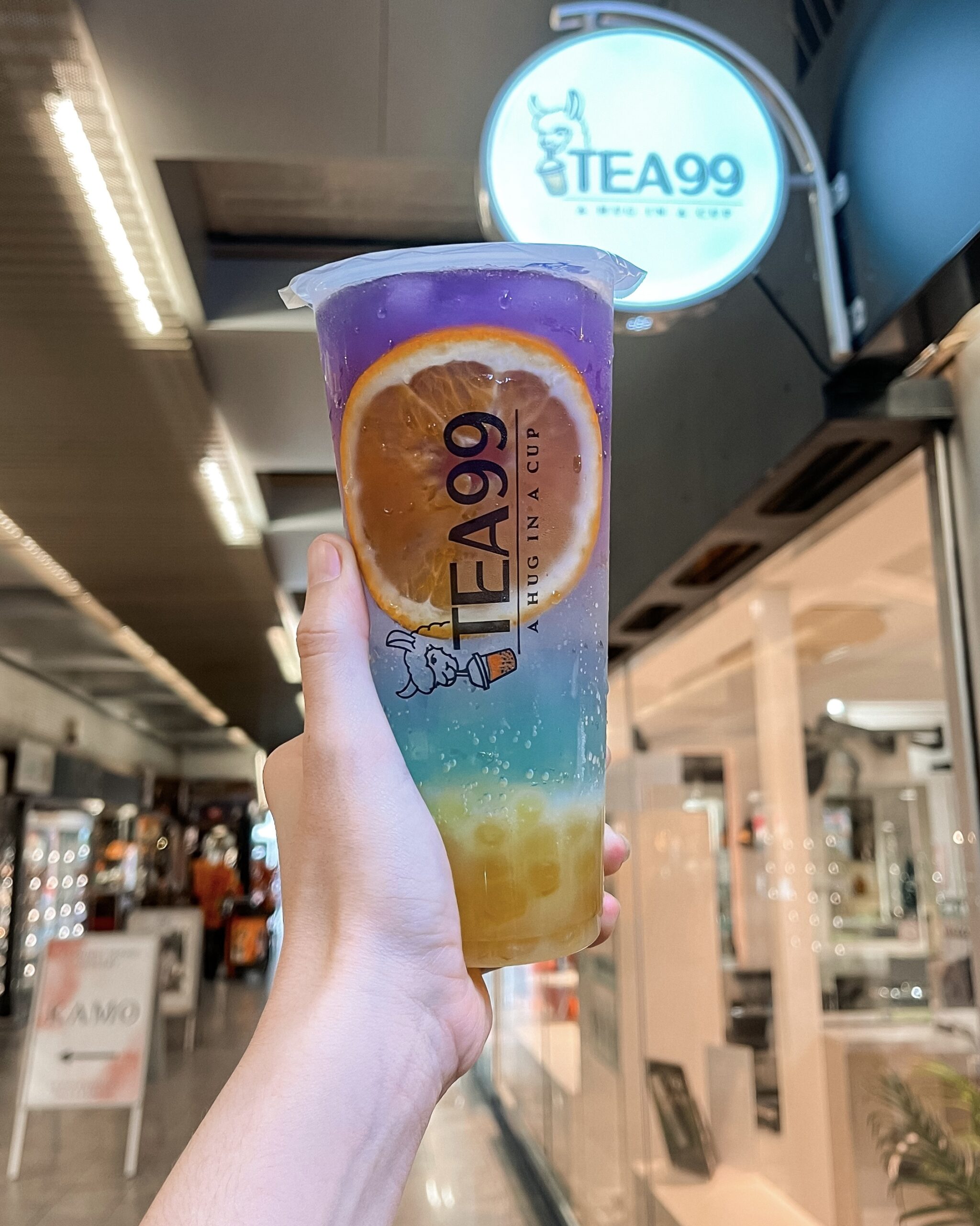 Farbintensives Bubble-Tea-Getränk mit Orangenscheibe von Tea99 Frankfurt, vor dem Geschäft gehalten