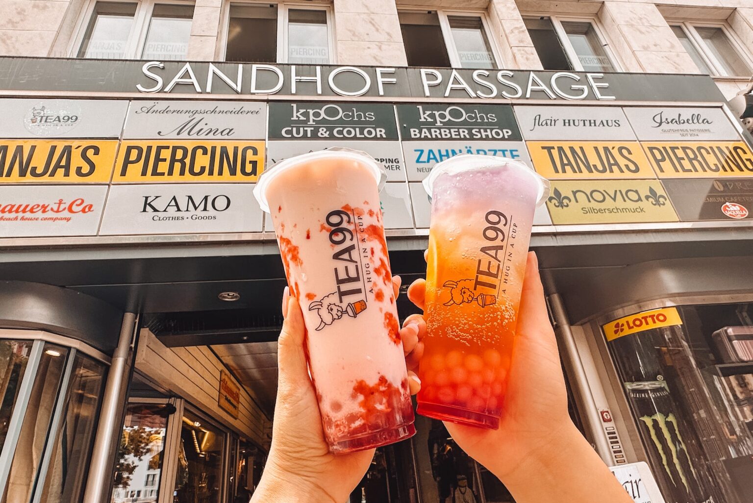 Zwei bunte Bubble Tea Getränke von Tea99 Frankfurt werden vor der Sandhof Passage in die Kamera gehalten