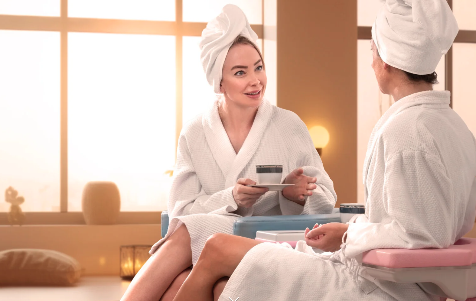 Zwei Frauen im Bademantel genießen eine entspannte Wellnesspause mit Tee