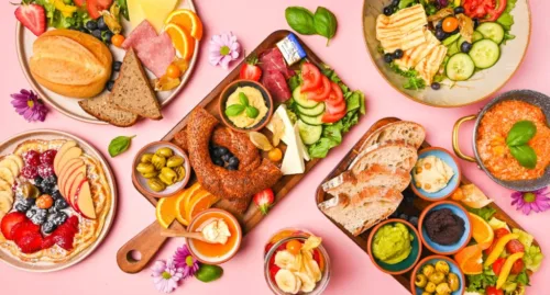 Vielfältige Frühstücksplatten mit Simit, Brot, Käse, Aufschnitt, Gemüse, Obst und Dips, stilvoll angerichtet auf rosa Hintergrund im Café Rot Dortmund