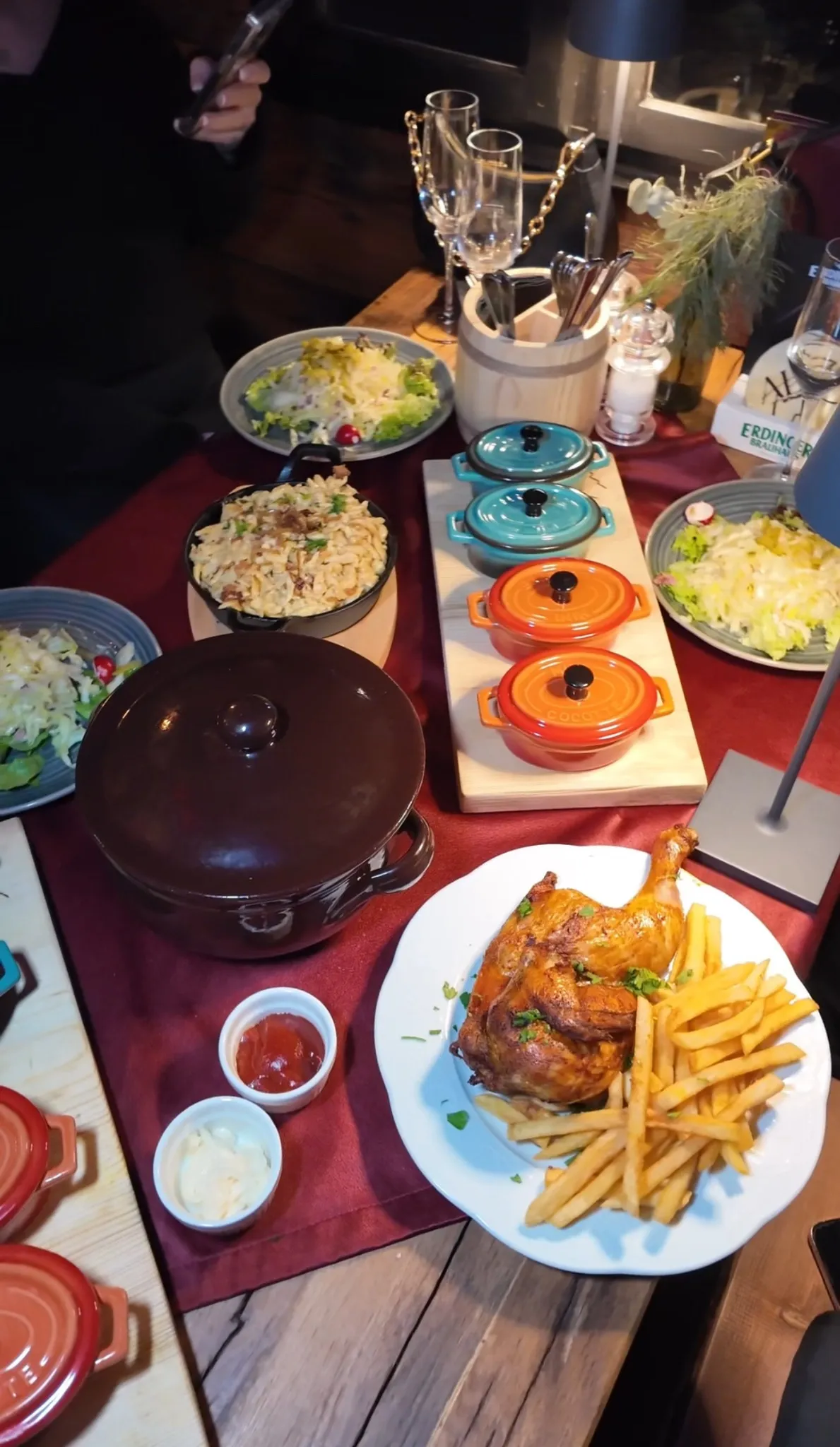 Reich gedeckter Tisch beim Knödelfest in der Alm Fernweh mit halbem Hendl, Pommes, Salaten, Aufläufen und traditionellen Töpfen mit Deckel