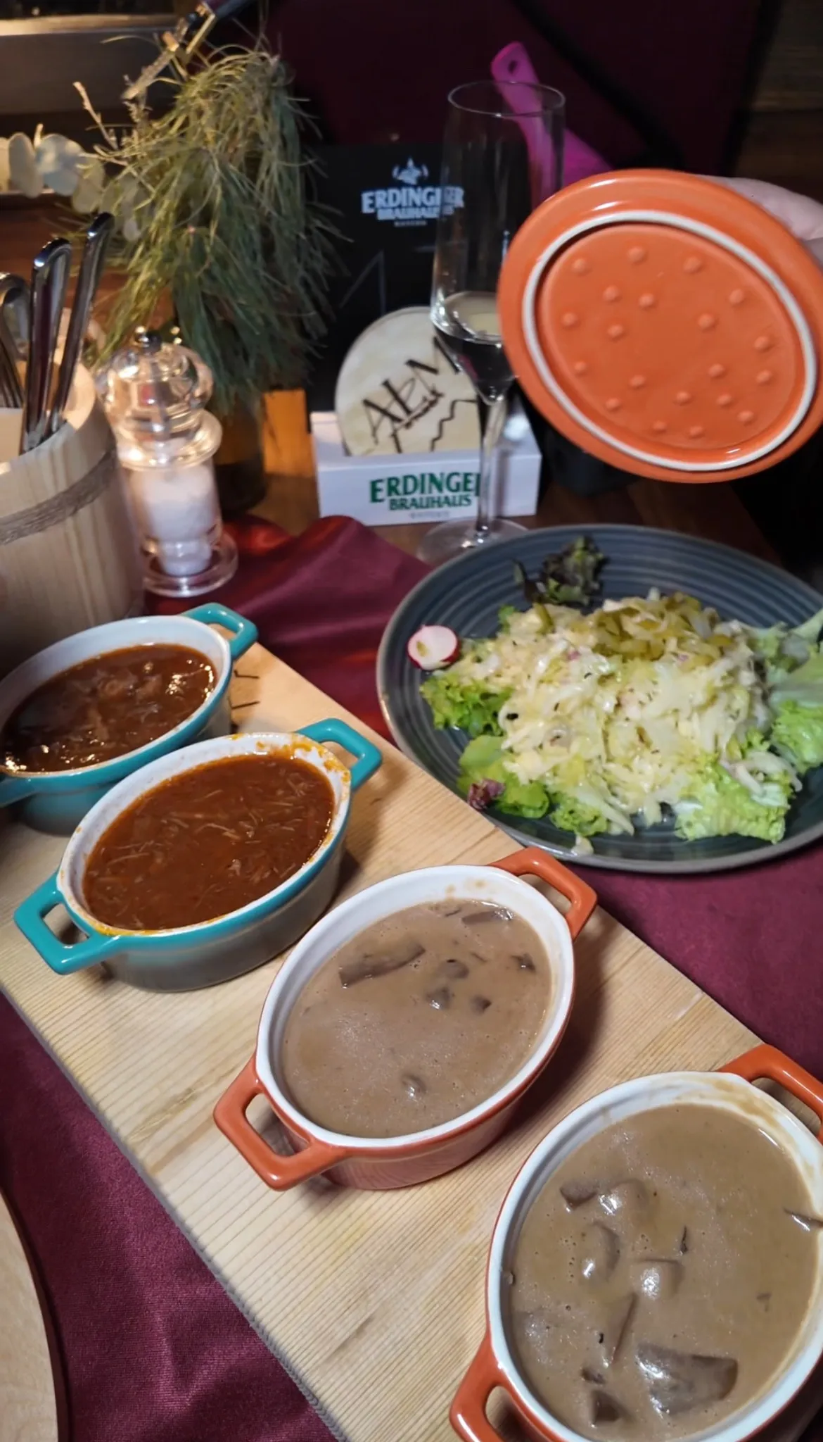 Drei verschiedene Saucen in bunten Keramikschalen auf einem Holzbrett, dazu ein Teller mit Krautsalat und rustikaler Deko bei der Alm Fernweh