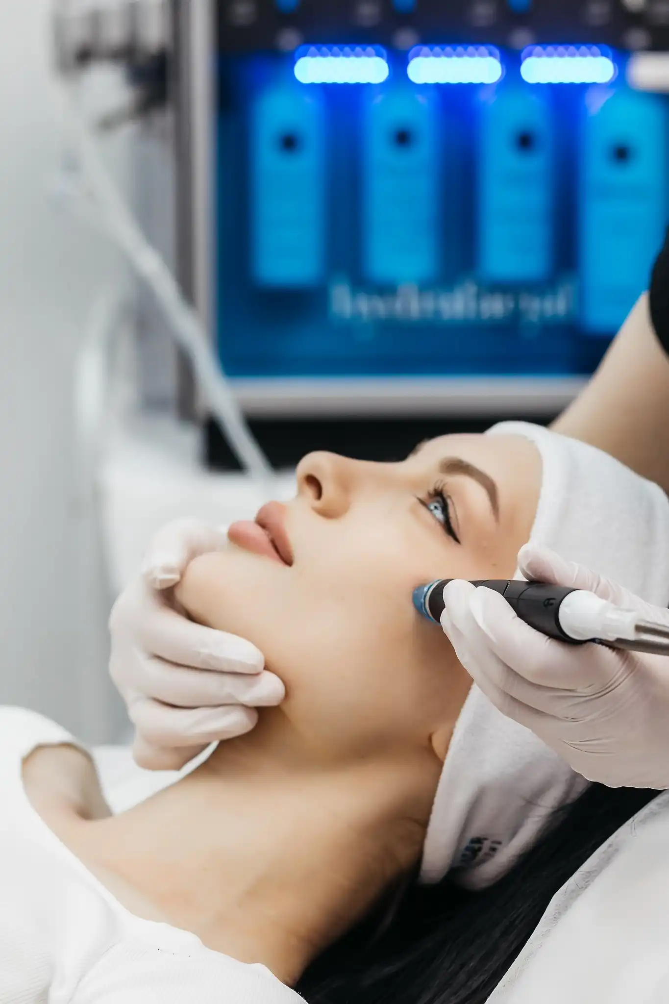 Frau erhält eine Aquafacial-Gesichtsbehandlung mit modernem Gerät, durchgeführt von einer Fachkraft mit Handschuhen