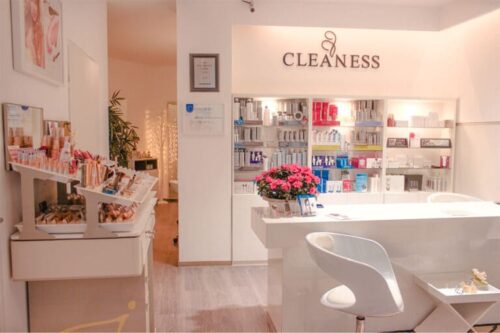 Heller Empfangsbereich im CLEANESS Institut Wetzlar mit modernen weißen Möbeln, dekorativen Blumen und einer Produktwand mit Kosmetikartikeln