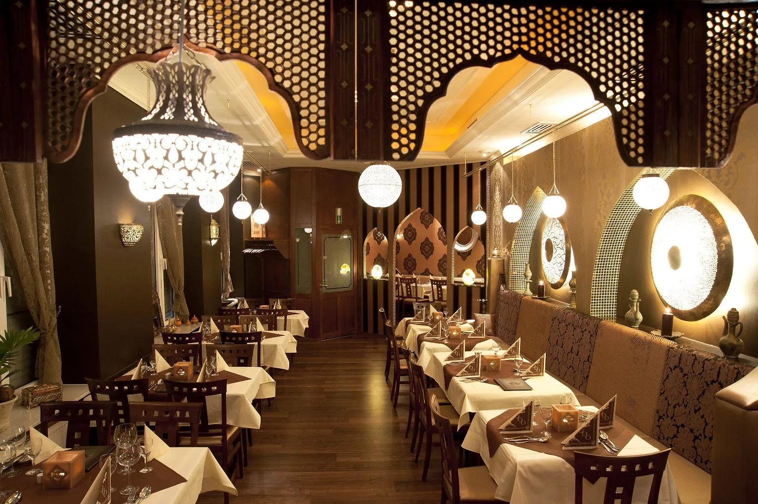 Elegantes orientalisches Interieur im Djadoo Restaurant Darmstadt mit gedeckten Tischen, Holzverzierungen, Kronleuchter und stilvollen Lichtakzenten