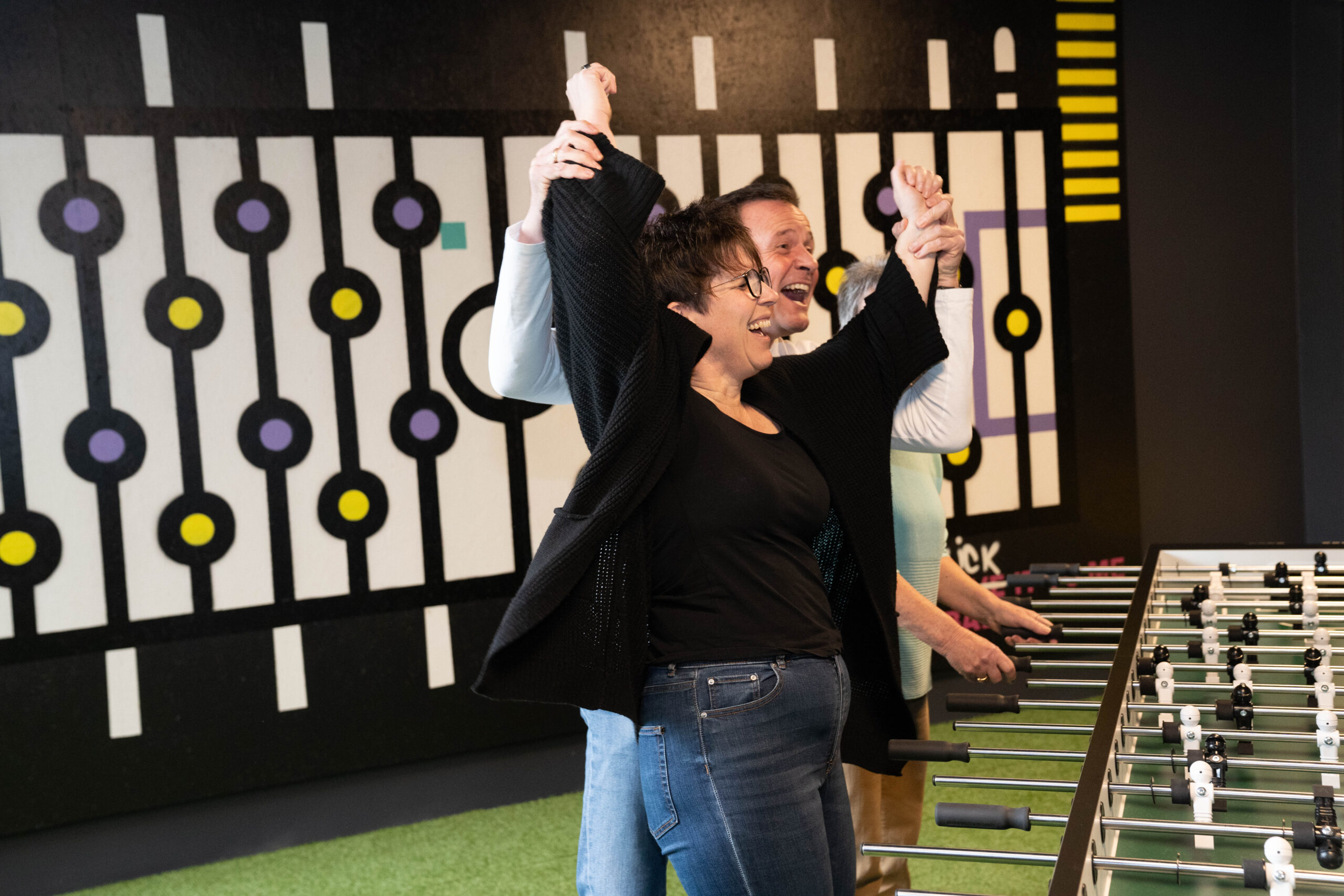 Frau jubelt mit erhobenen Armen bei einem interaktiven Spiel in der Face Off GmbH in Rüsselsheim am Main, während ein Mann hinter ihr mitlacht