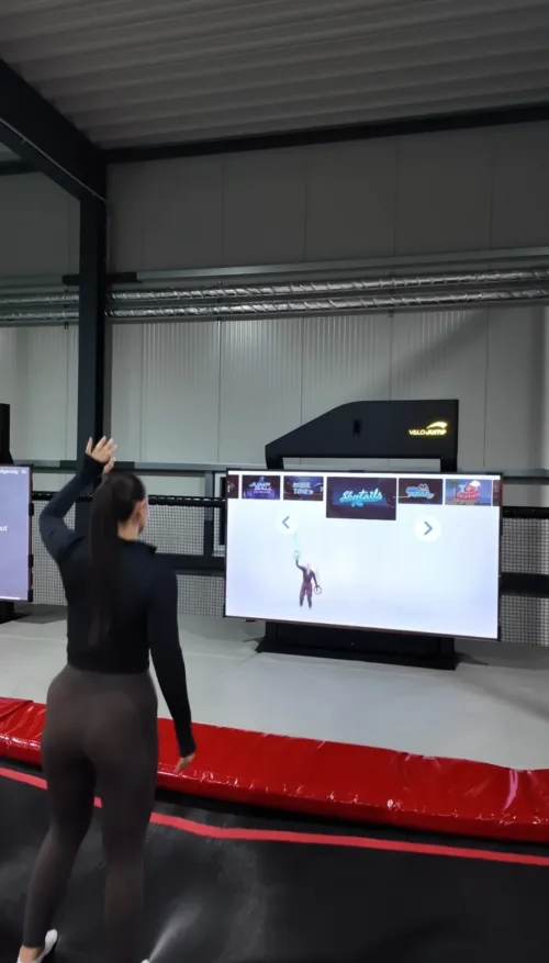 Frau spielt ein Virtual-Reality-Spiel im FunFusion Wetzlar, gesteuert durch Körperbewegungen vor mehreren großen Bildschirmen in einer modernen Indoor-Arena