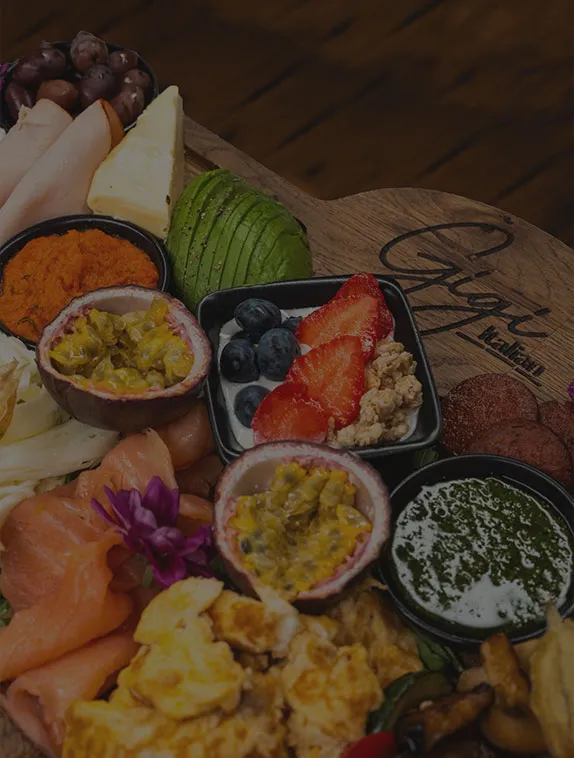Frühstücksplatte im Gigi Italian Köln mit verschiedenen Aufstrichen, Käse, Avocado, Lachs, Obst und Dips auf einem gravierten Holzbrett serviert