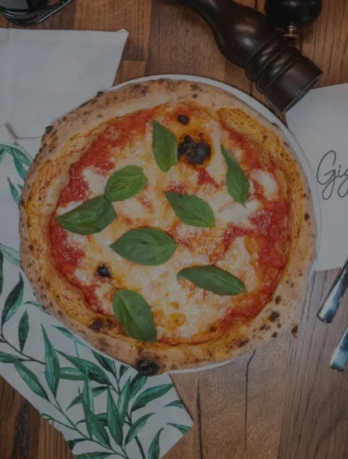 Klassische Pizza Margherita mit frischem Basilikum, Mozzarella und Tomatensauce, serviert auf einem weißen Teller im Gigi Italian Köln