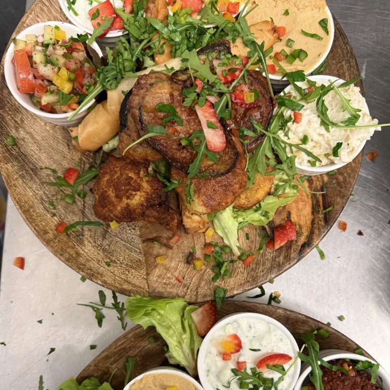 Tapasplatte mit nepalesischen Spezialitäten aus dem Hamro Nepali Restaurant Frankfurt, darunter Pakora, Dips, Chutneys, Salate und Joghurt, serviert auf rustikalem Holzbrett