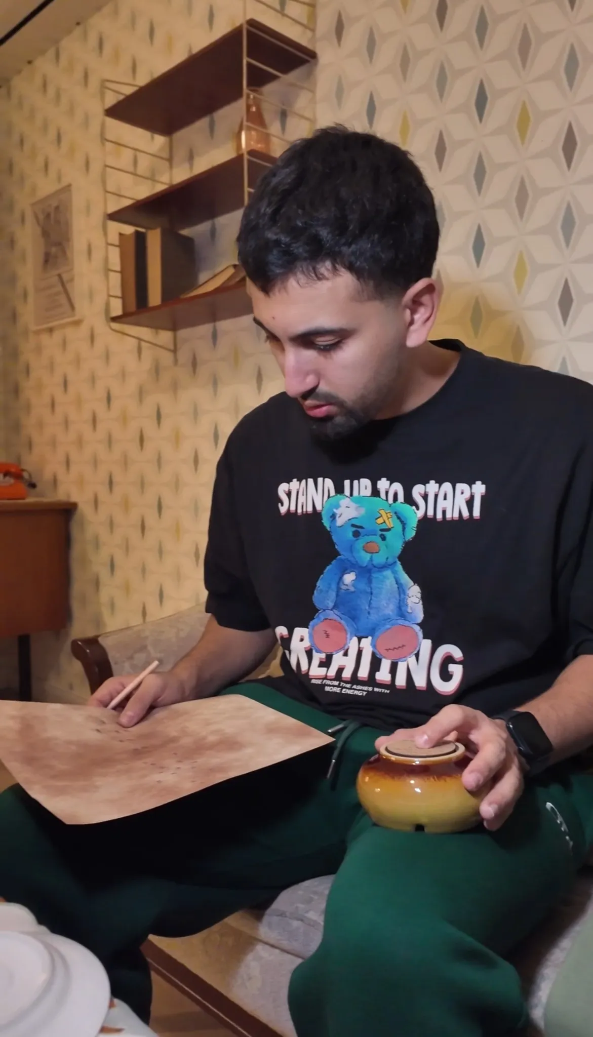 Teilnehmer im Escape Room „Muriel_Ingrid“ studiert konzentriert eine alte Karte oder ein Dokument und hält eine Urne in der Hand – Szene im Retro-Wohnzimmerstil