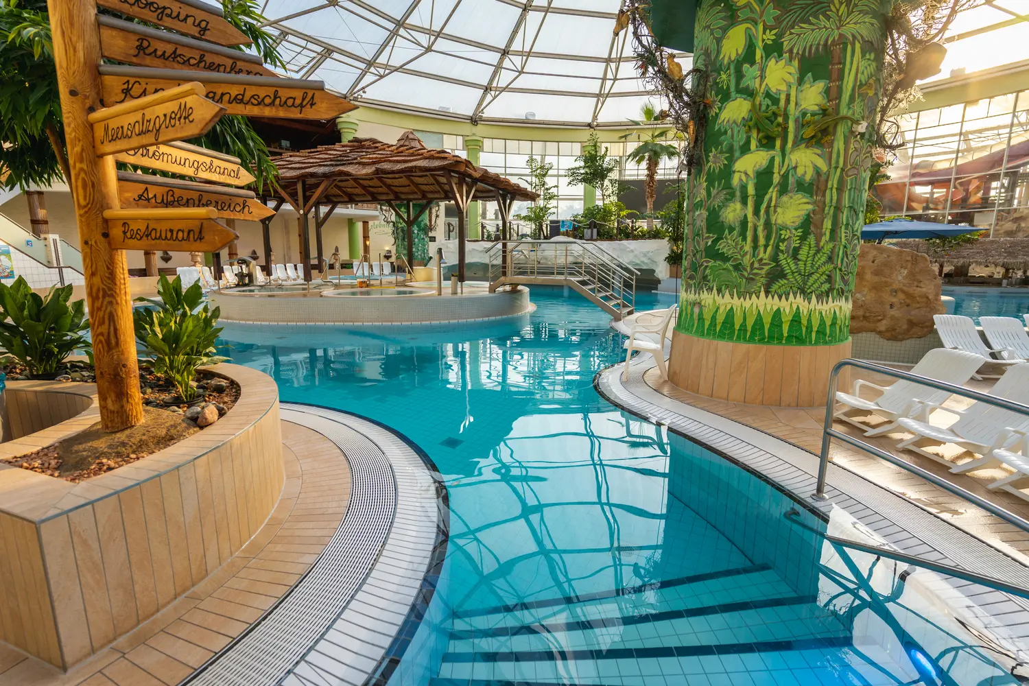 Tropisch gestalteter Innenbereich im AQUALAND Köln mit Palmen, Pool, Bambus-Dekor und Glasdach