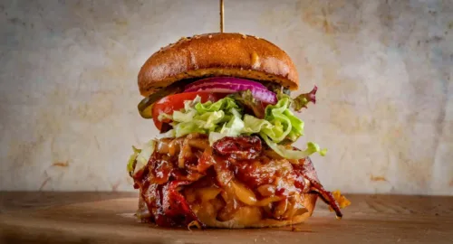 Saloon Hickory Burger aus dem Red Barn BBQ Restaurant mit Pulled Pork, BBQ-Sauce, Käse, Salat, Tomate, Gurke und roten Zwiebeln im Brioche-Bun