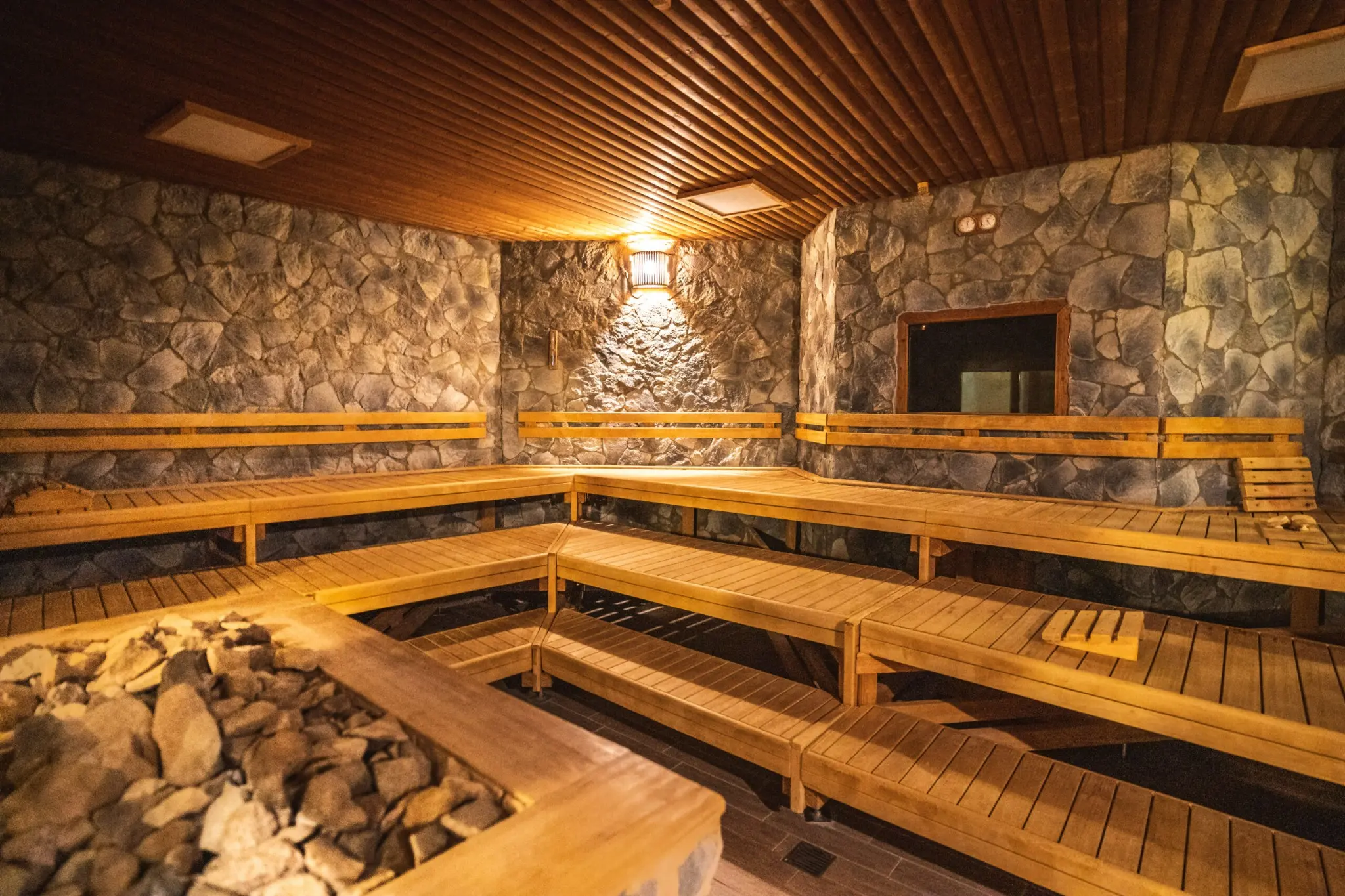 Große rustikale Felsensauna, Holzliegen und zentralem Saunaofen im Aqualand