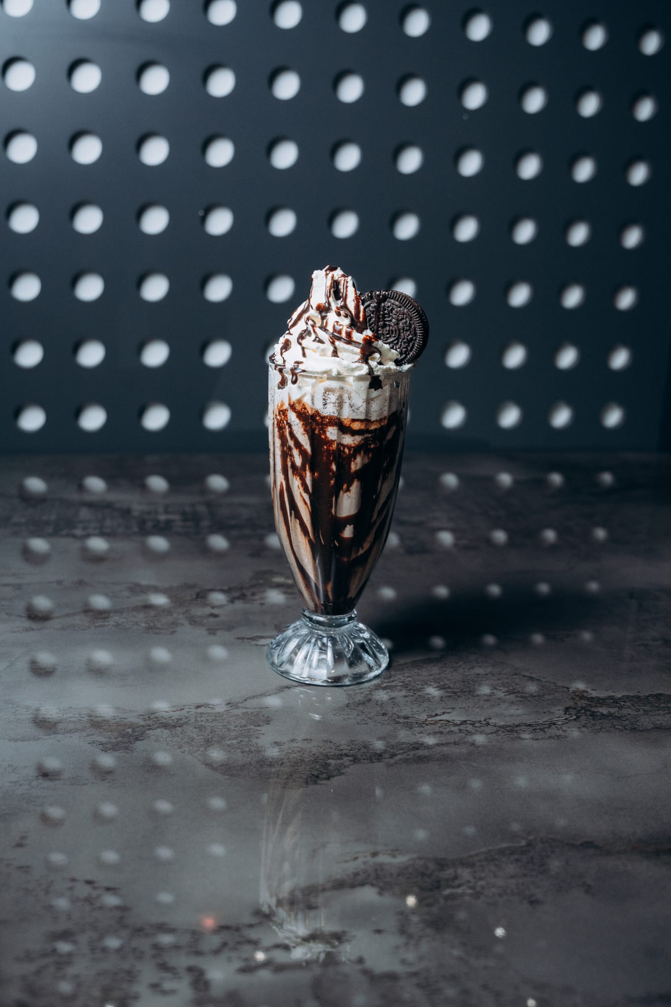 Oreo-Milchshake im hohen Glas mit Sahne, Schokosauce und Oreo-Keks-Topping, serviert im modernen Interior von Shiva Food and More Dinslaken