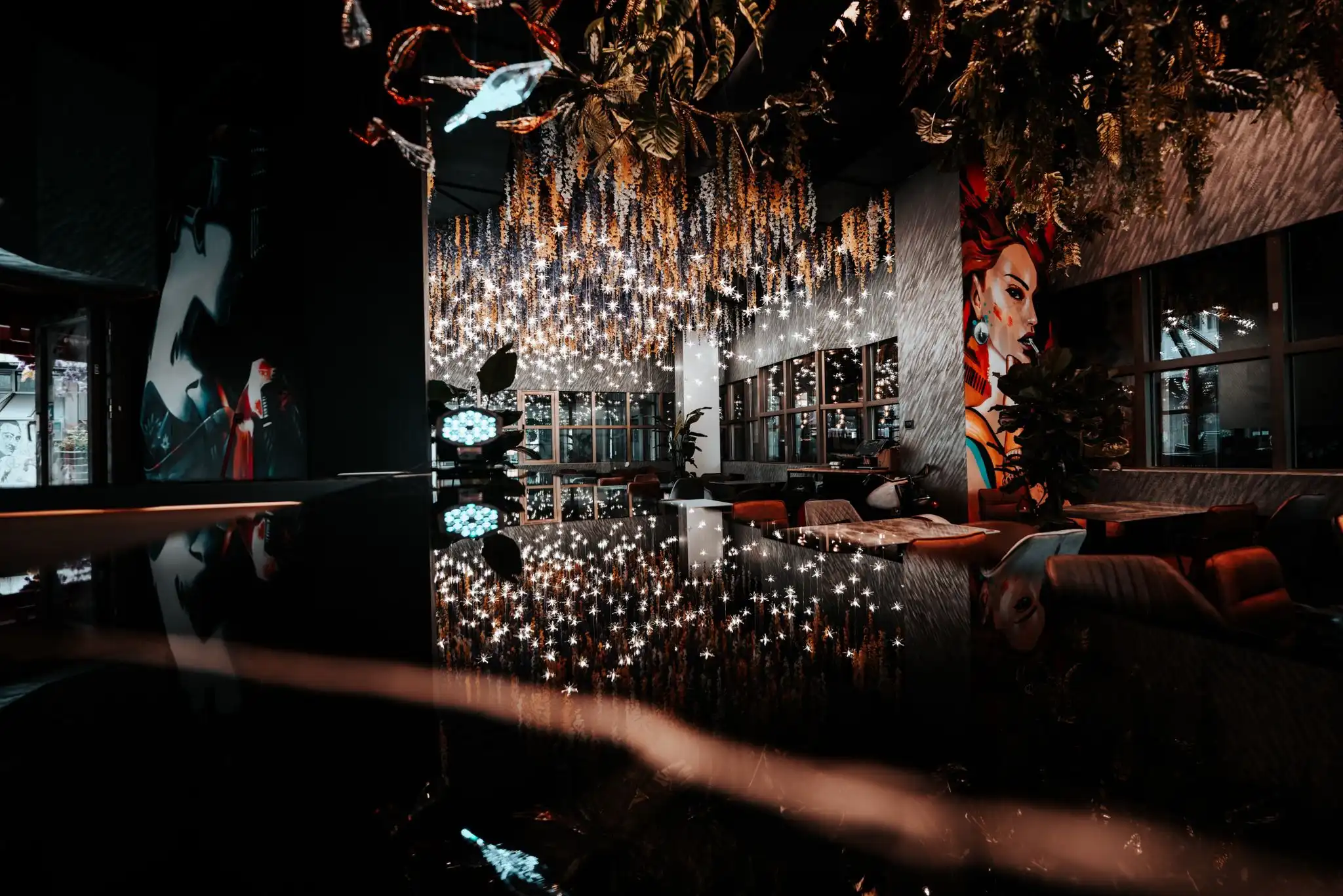 Stilvoller Innenraum der Bar im Yozora-17 Fusion Sushi Wiesbaden mit üppiger Deckeninstallation, Spiegelungen auf dunklem Tisch und kunstvoller Wandmalerei