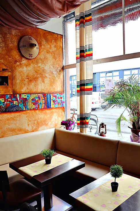 Bunter, gemütlicher Fensterplatz mit ethnischem Wanddesign im Adabina Restaurant Frankfurt