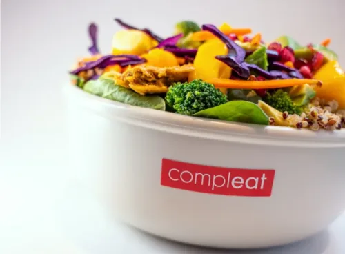 Bunte vegetarische Bowl von Compleat Nordend mit Brokkoli, Mango, Rotkohl, Spinat, Karotten und Tofu in einer weißen Schüssel