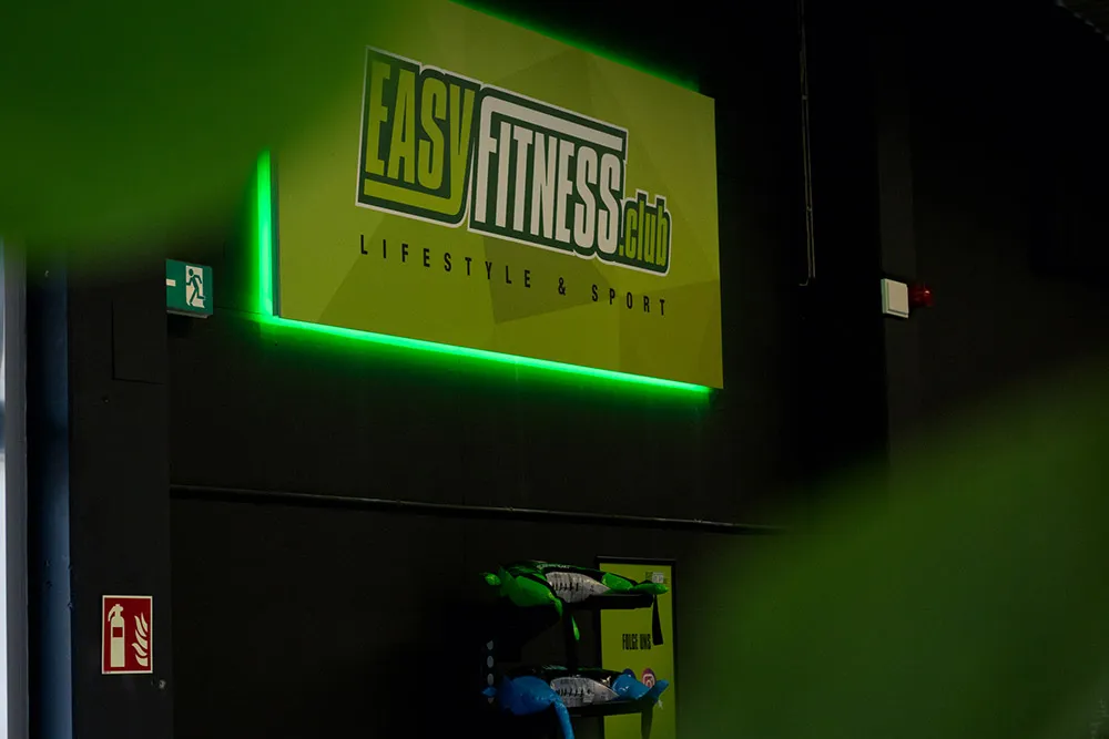 Leuchtendes EASYFITNESS.club Logo an der Wand des Fitnessstudios