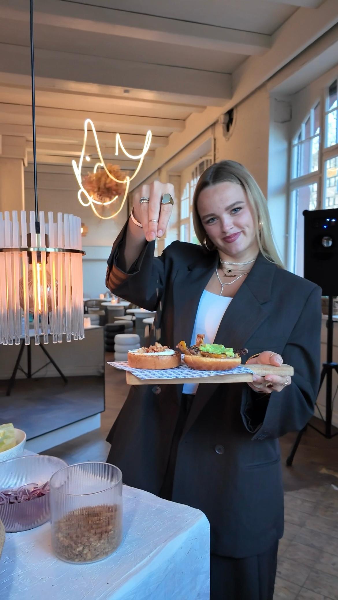Frau präsentiert zwei Smash Burger auf einem Tablett in einem stilvollen Restaurant