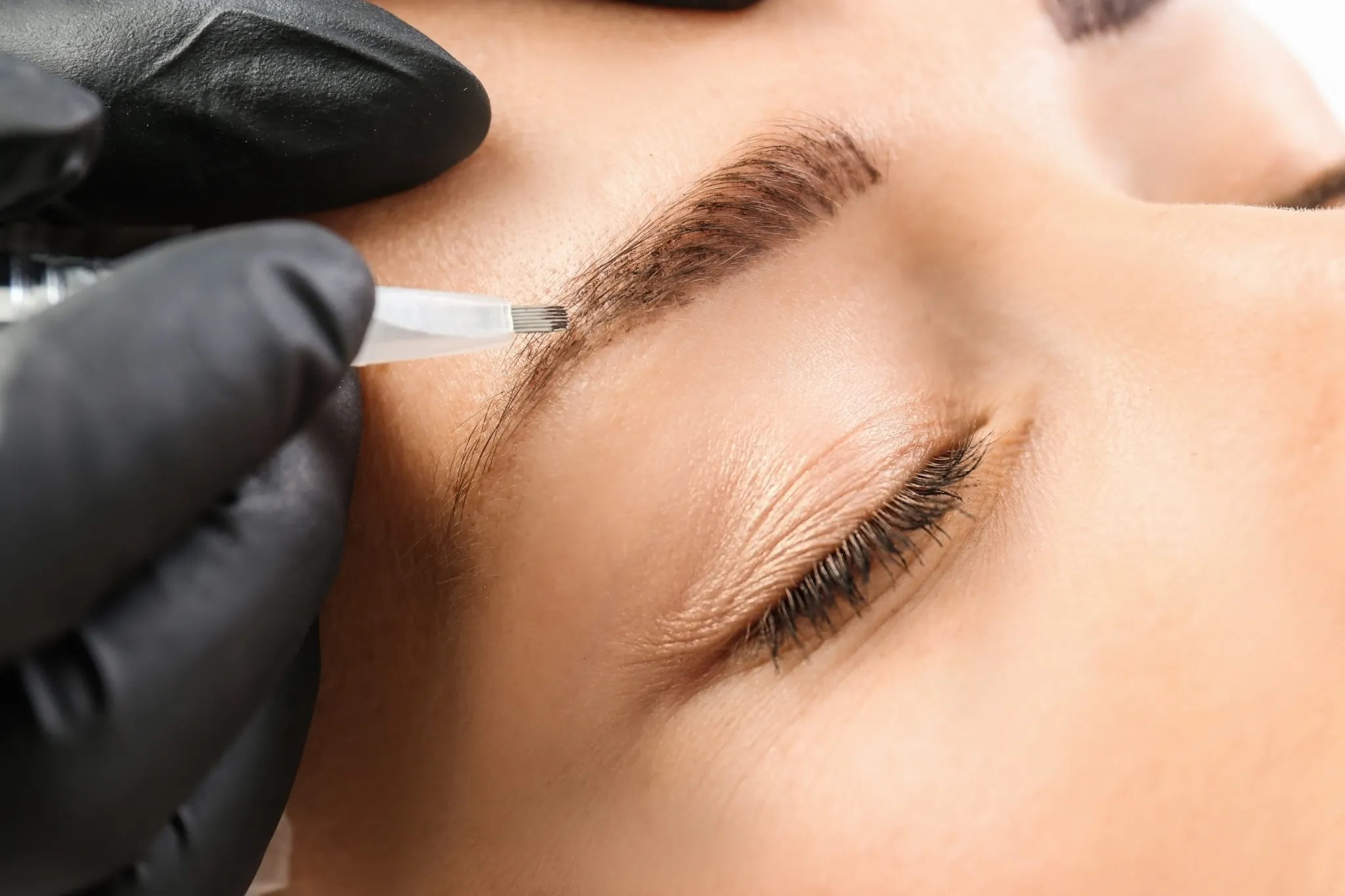 Detailaufnahme einer Microblading-Behandlung an der Augenbraue einer Frau
