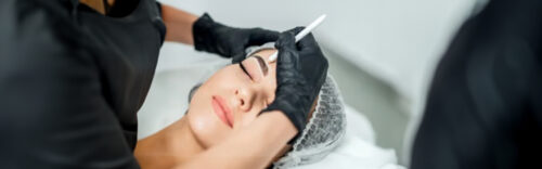 Kosmetikerin vermisst die Augenbrauen einer Frau zur Vorbereitung auf ein Microblading