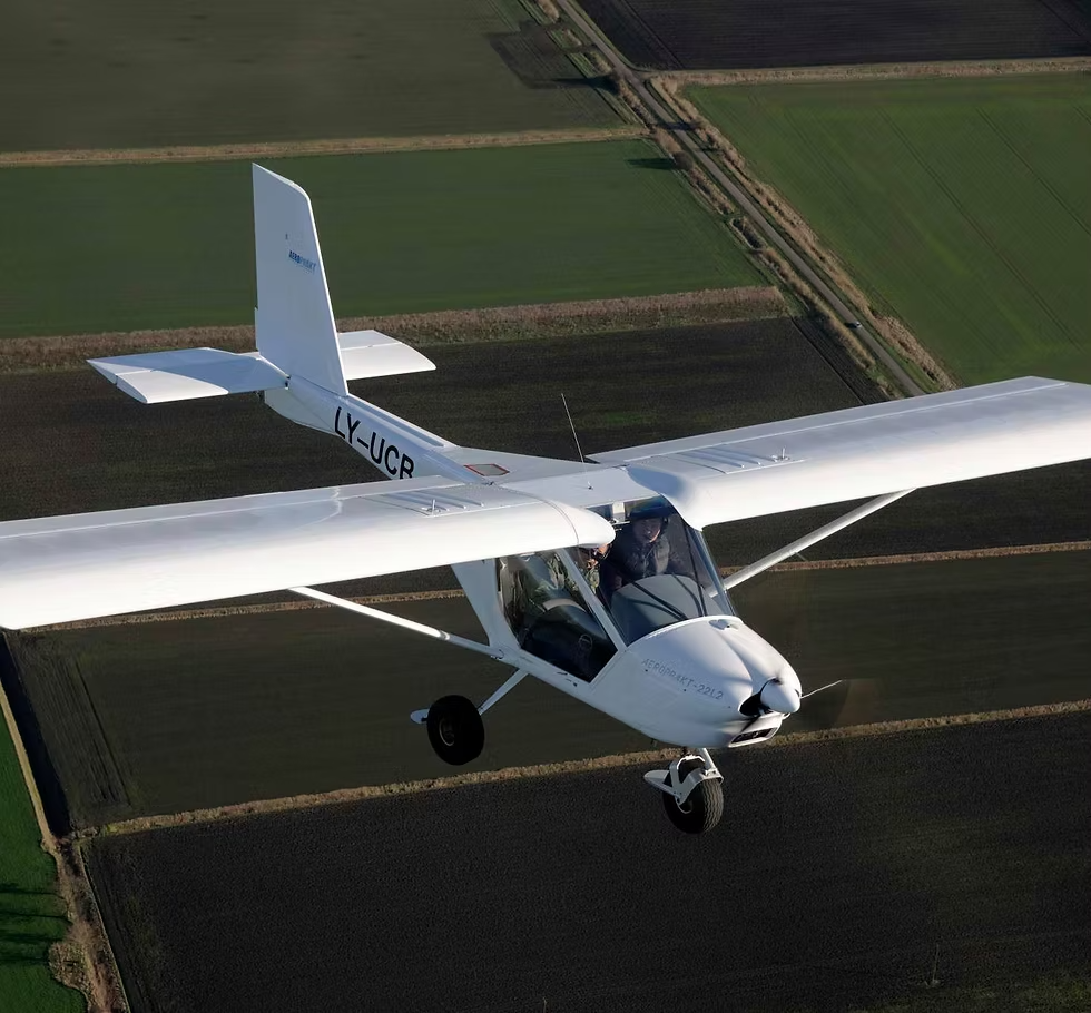 Weißes Flugzeug von Profievents Sankt Augustin im Flug über Felder bei klarem Wetter, frontal aus der Luft fotografiert