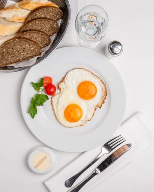 Zwei Spiegeleier auf Brot mit Tomate und Petersilie im Café Restaurant Manzini in Berlin