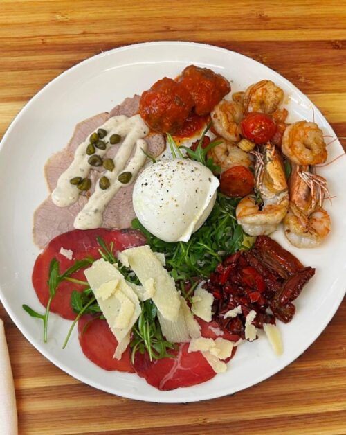 Italienische Antipasti-Platte mit Burrata, Garnelen, Vitello Tonnato, Rindercarpaccio, getrockneten Tomaten und Rucola im Ristorante La Vetra