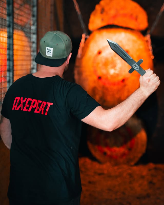 Mann mit schwarzem „AXEPERT“-Shirt beim Messerwerfen in Weiterstadt vor Zielscheibe aus Holz