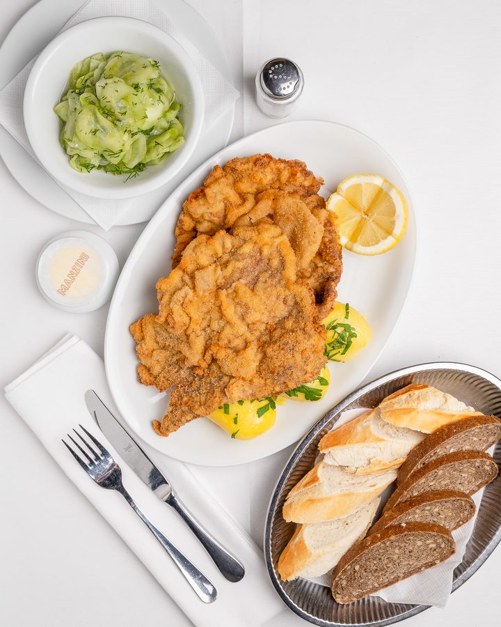 Wiener Schnitzel mit Kartoffeln, Gurkensalat und Brotauswahl im Café Restaurant Manzini in Berlin