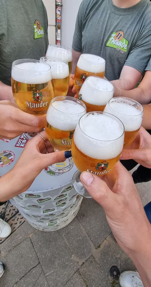 Freunde stoßen mit frisch gezapftem Bier in der 11 Freunde Bar in Essen an