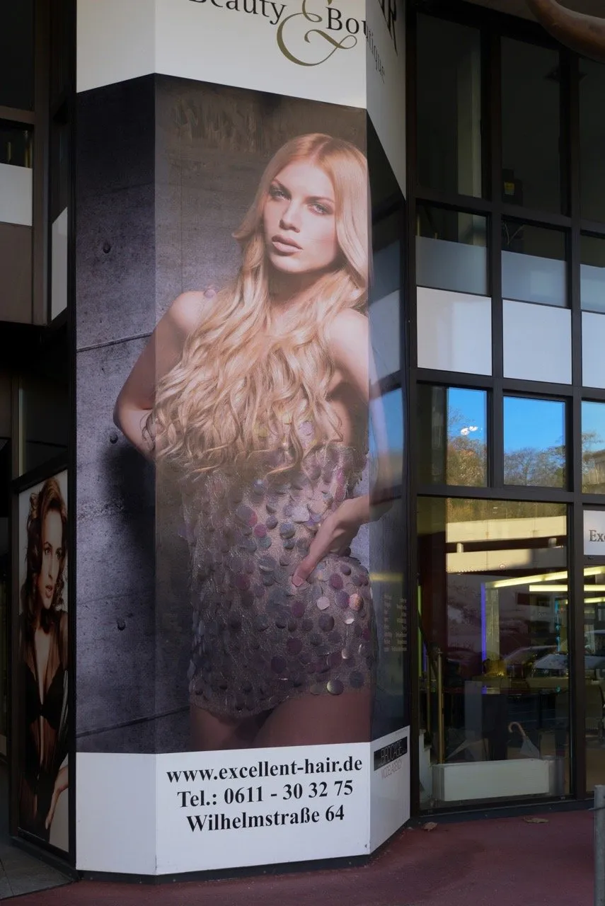 Außenwerbung von Excellent Hair Wiesbaden mit großem Plakat an der Salonfassade