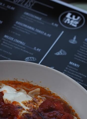 Nahaufnahme von Manti mit Joghurt und Tomatensauce vor der Speisekarte im Lume Café Bar Mannheim