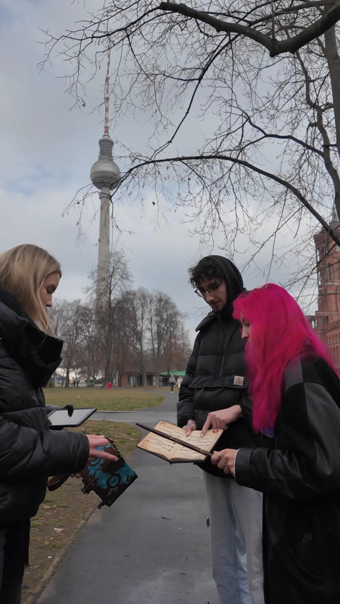 Gruppe mit Rätselbuch bei der Outdoor Escape Tour in Berlin vor dem Fernsehturm