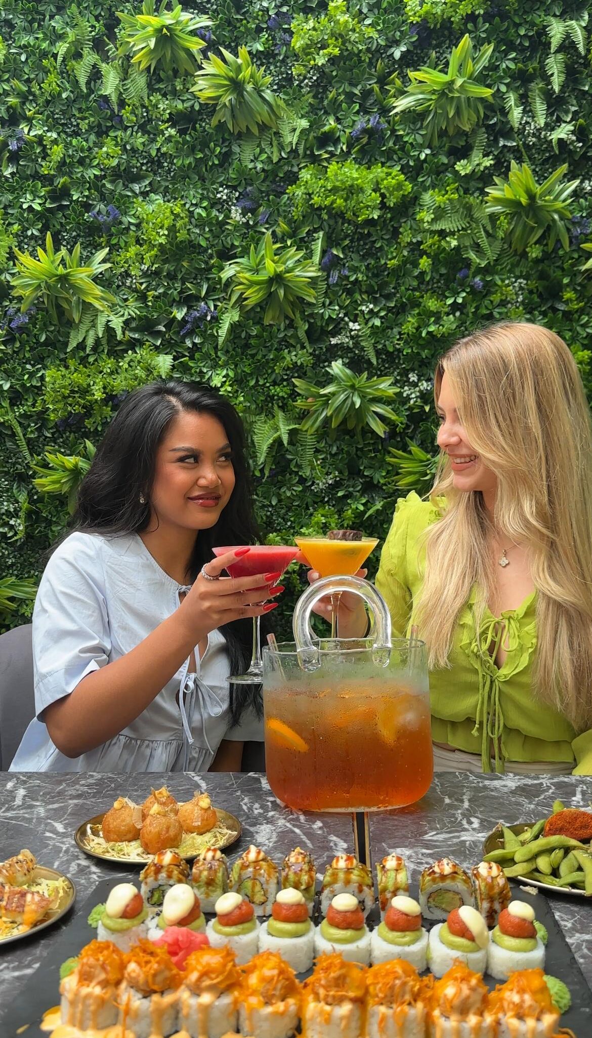 Zwei Frauen stoßen mit Aperol Spritz im Oishinbo Dortmund im grünen Außenbereich an